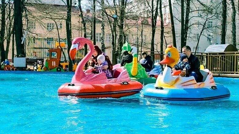 Люди катаются на лодках-утках в парке аттракционов