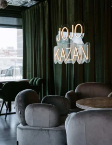 Неоновая вывеска «JOJO KAZAN» над креслами в кафе «Jojo»