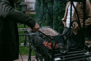 Люди готовят шашлык на мангале у базы отдыха «Фламинго и кокос»