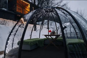 Прозрачный купол с гирляндами и столом внутри глэмпинга «For-rest»