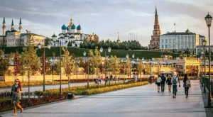 Люди гуляют по Кремлёвской набережной с видом на храмы и башню