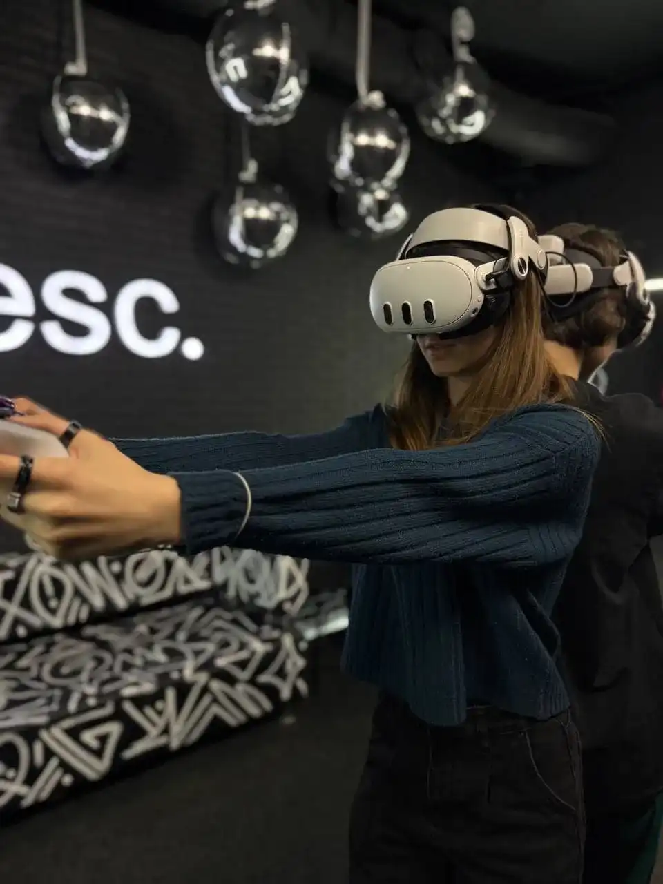 Гостья целится контроллерами в VR-шутере