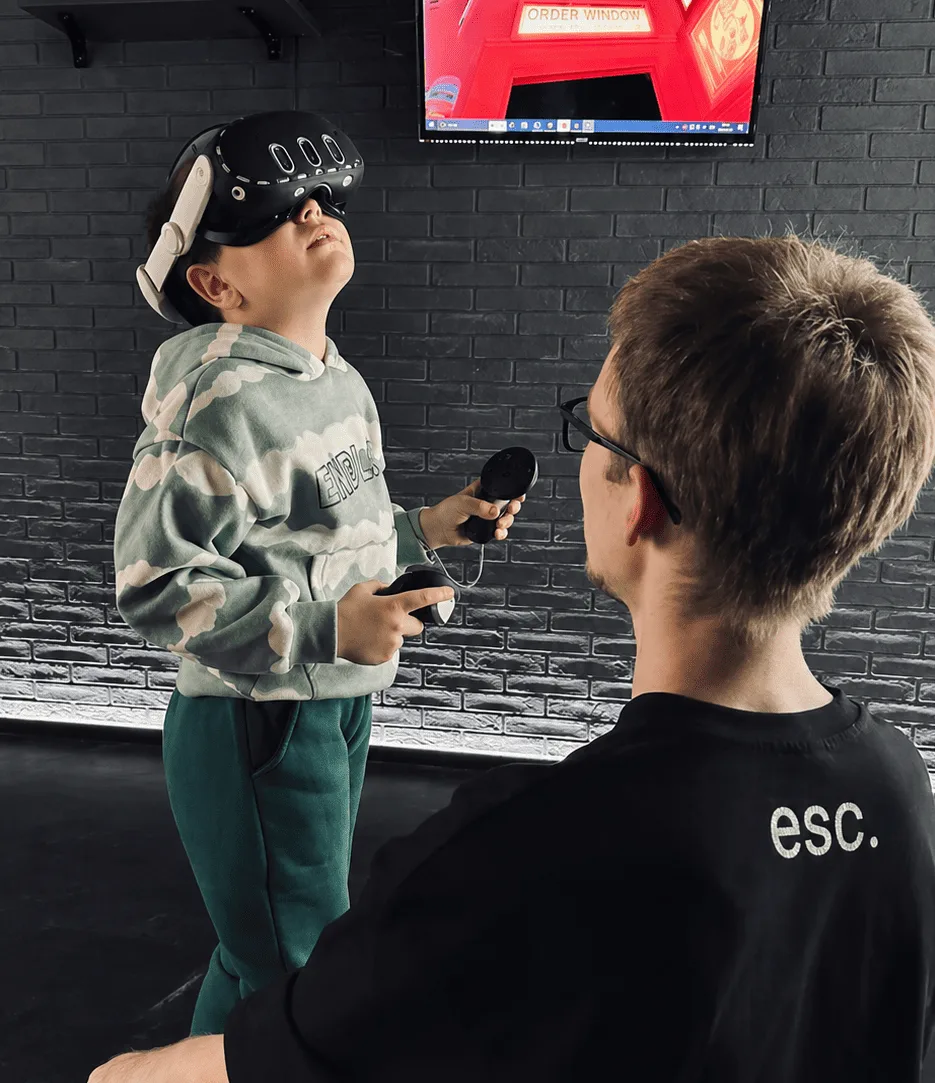 Мальчик играет в VR, рядом администратор-ведущий