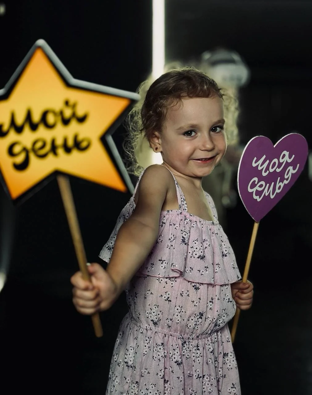Девочка с табличками «Мой день» и «Моя семья» на празднике